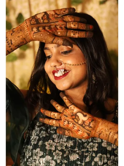 A candid shot capturing the beauty of bridal mehendi. The detailed patterns on her hands and arms are a central part of her celebratory look.