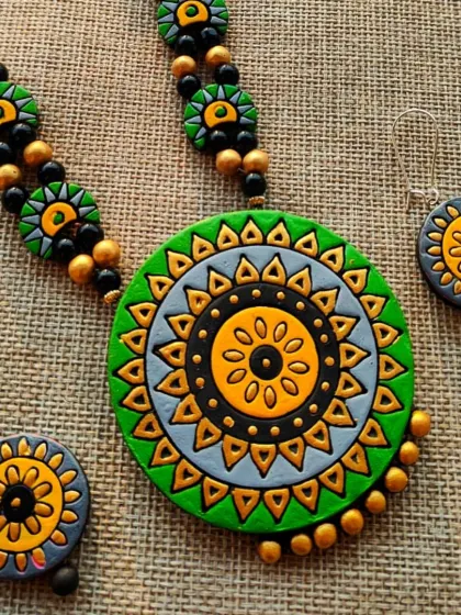 A long 'haram' style necklace with a green and grey mandala pendant and matching hanging earrings.