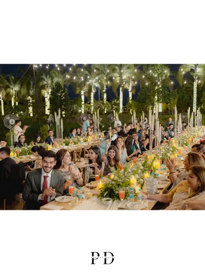 Guests enjoying the intimate dinner party. The long-table setup encourages conversation and creates a warm, communal atmosphere.