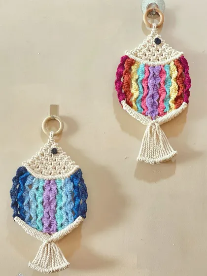 A pair of colorful macrame fish, each with a unique color pattern. These look wonderful in a bathroom or a beach-themed room.
