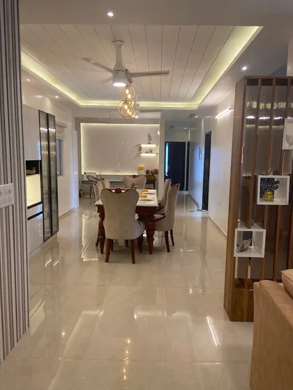 The same open-plan space, showing the flow from the living area to the dining table and crockery unit in the background.