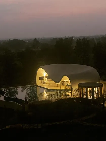 An aerial view of the Aqua Pool & Spa at dusk, showing how the structure glows like a lantern in the Nandi valley, a serene beacon nestled among the trees.