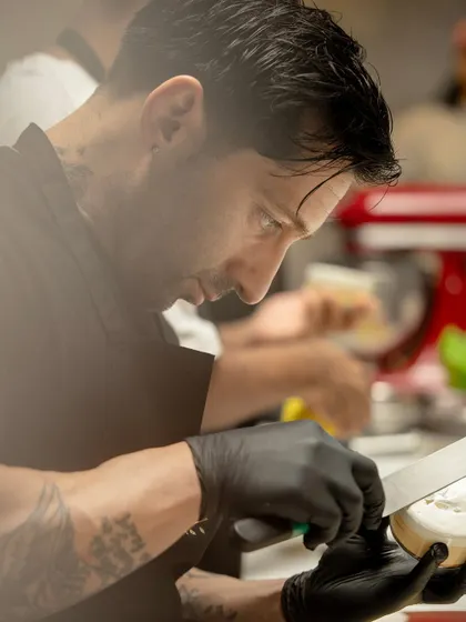 A close-up of a chef's hands, showing the concentration and skill required for high-level pastry work.