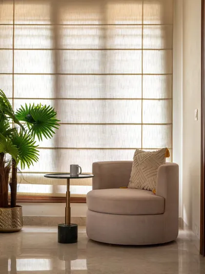 This cozy corner shows how simple elements can create a perfect reading spot. A comfortable armchair, a small side table for your coffee, and soft, filtered light from the roman blinds make it an ideal place to unwind.