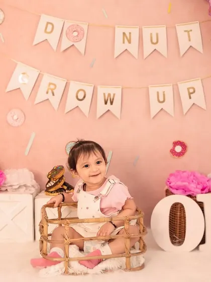 A sweet smile from inside a basket, surrounded by donuts and pink decor. I use various props to create different compositions and keep the baby engaged.