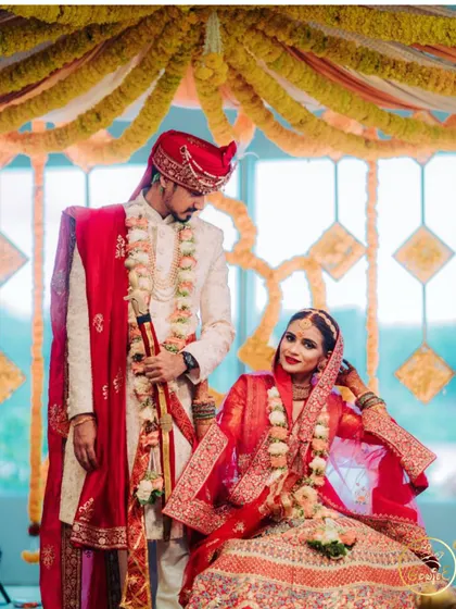 The bride and groom posing on their wedding stage, looking regal in their traditional attire.