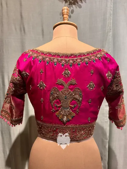 The back of the hot pink blouse, featuring a majestic Gandaberunda motif.