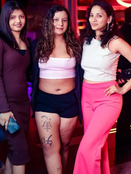 A stylish group of friends posing against the vibrant backdrop of the club.