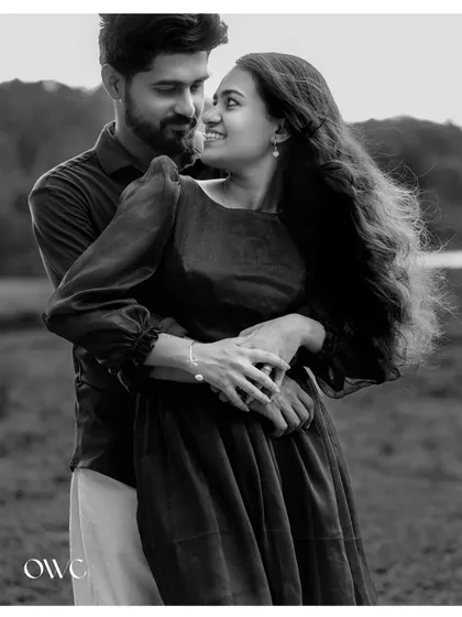 A timeless black and white portrait of a couple embracing, with the wind catching her hair, adding a touch of romance.