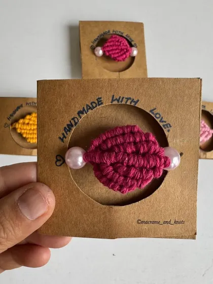 A close-up of the packaged macrame Rakhi, showing the pearl details and the rustic kraft paper card.