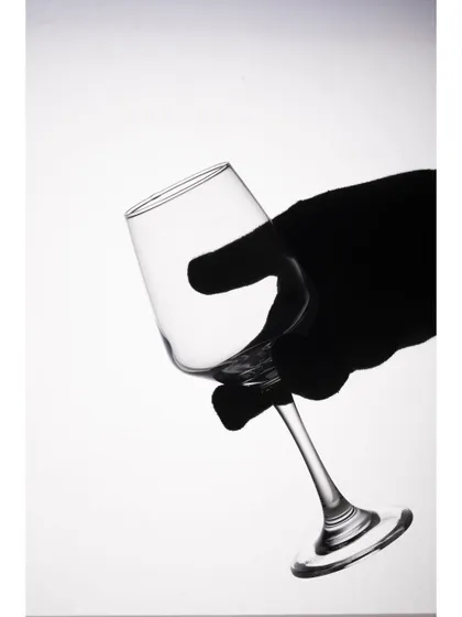 A close-up of a gloved hand holding a wine glass, shot in a high-key lighting setup. This image highlights the delicate form of the glass and is perfect for demonstrating product handling.
