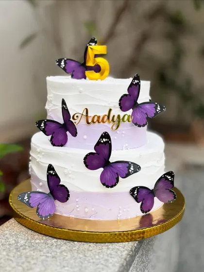 A pretty two-tier butterfly cake for a fifth birthday. The purple ombre buttercream is decorated with beautiful, realistic purple butterflies.