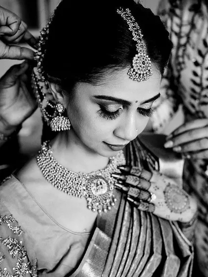A candid black and white moment from the getting ready process. The focus on the bride's face as her hair is styled captures the quiet anticipation before the ceremony.