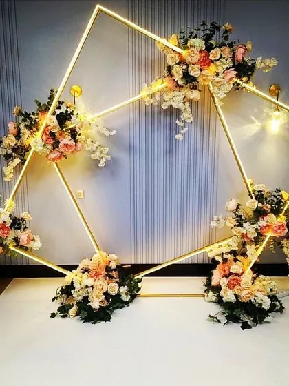This geometric diamond-shaped backdrop with integrated LED lighting is a modern and glamorous option for a stage or photo wall. The florals add a soft, romantic contrast to the sharp lines.