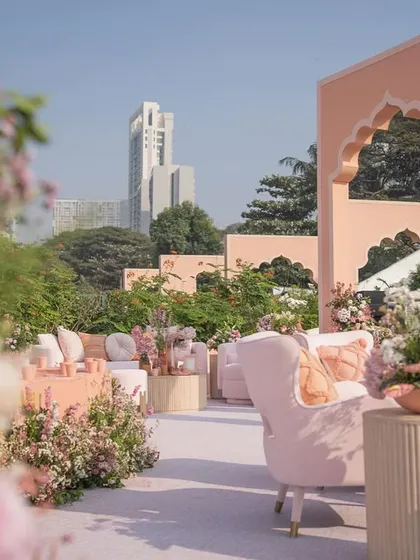 A view through the flowers shows the elegant seating arrangements set against the backdrop of the city and the custom-designed arches.