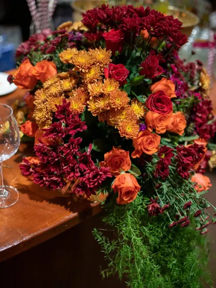 A close-up of the bar arrangement, showing the rich textures of the red and orange blooms against a cascade of fresh greenery.