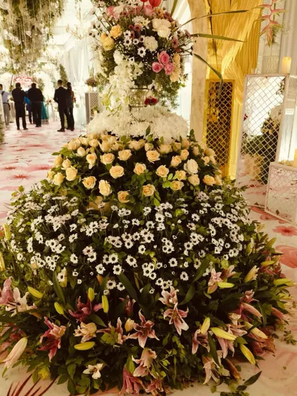 A magnificent, towering floral centerpiece, created with layers of roses, lilies, and daisies, serving as a stunning focal point in the reception hall.