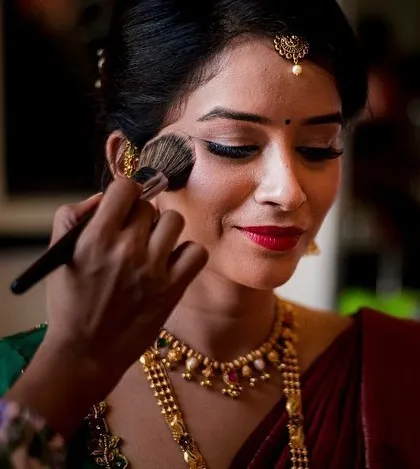 A close-up of the bride's makeup being applied, capturing the artist's careful touch and the bride's serene expression.