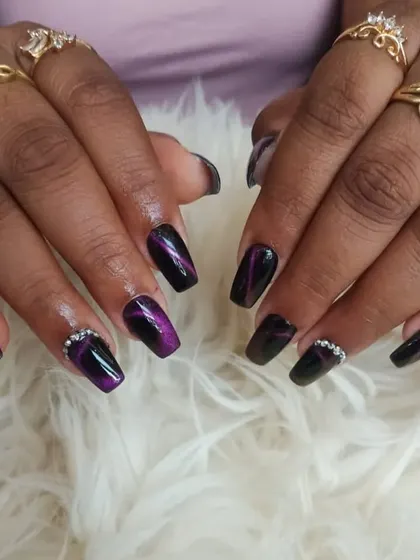 A full set of the purple cat-eye nails, complete with rhinestone accents and worn with beautiful rings.