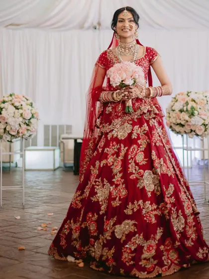 Holding a delicate bouquet, this bride's smile says it all. We styled this traditional red lehenga with timeless jewelry for a look that is both classic and personal.