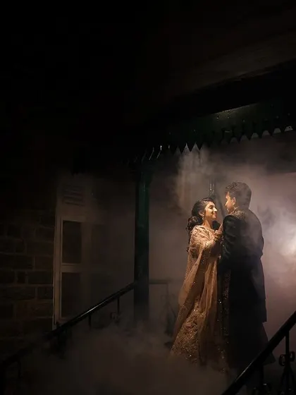 A mysterious and romantic portrait using smoke. The couple emerges from a cloud of fog on a staircase, creating a dramatic and cinematic feel for their reception entrance.