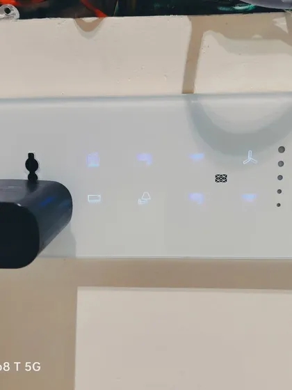 This image shows the clean installation of a white smart touch panel, complete with a standard power socket. The panel provides intuitive touch controls for multiple appliances and lighting scenes.