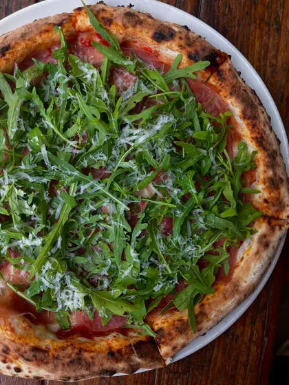 An overhead shot of the Prosciutto di Parma e Rucola, showing the generous topping of fresh arugula and parmesan.