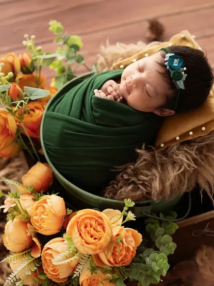 A wider angle of the green and orange floral setup, showing the baby peacefully asleep.