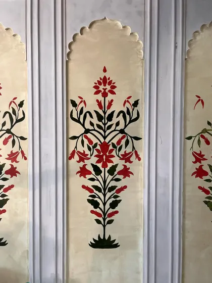 A close-up of the hand-painted Mughal floral panels, showcasing the symmetrical design and the classic red and black color palette.