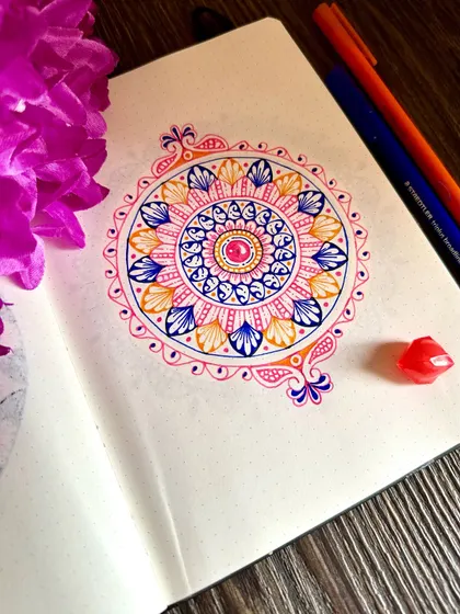 A beautiful ornate mandala drawn in a notebook. The pink, blue, and orange colors work so well together, creating a vibrant and joyful piece.