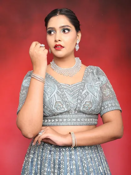 A close-up portrait showing the details of the makeup and jewelry. The red lip adds a classic touch to the modern eye makeup.