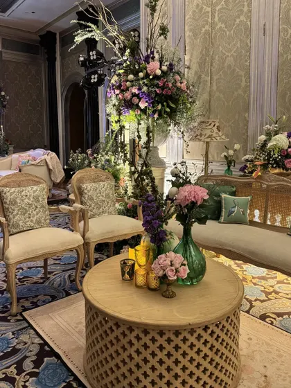 An elegant lounge area with vintage furniture, tall floral arrangements, and carefully chosen cushions, demonstrating a keen eye for sophisticated styling.