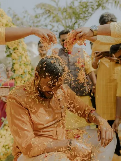 The groom gets a shower of flower petals from his friends, a classic moment of celebration during the Haldi.