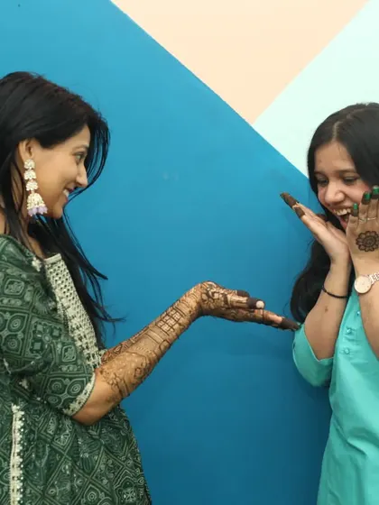 Capturing the fun interactions between family and friends is a key part of my pre-wedding photography. Here, two sisters share a laugh while admiring the fresh mehandi against a colorful backdrop.