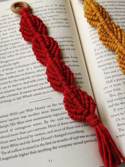 A close-up of the red macrame bookmark, showing the intricate knots that form the repeating pattern.