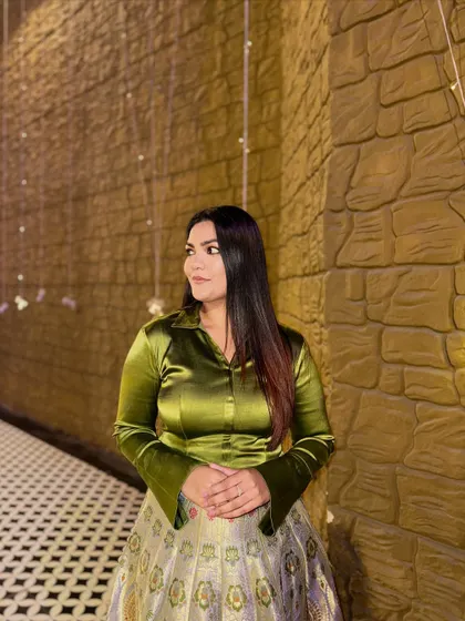 The olive green satin shirt brings a modern, jewel-toned feel to this traditional printed skirt, creating a balanced and eye-catching ensemble.