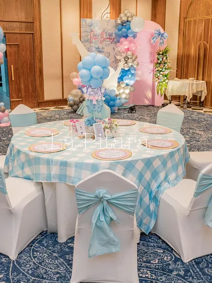 An elegant table setting with a blue gingham tablecloth and matching blue sashes on the chairs.