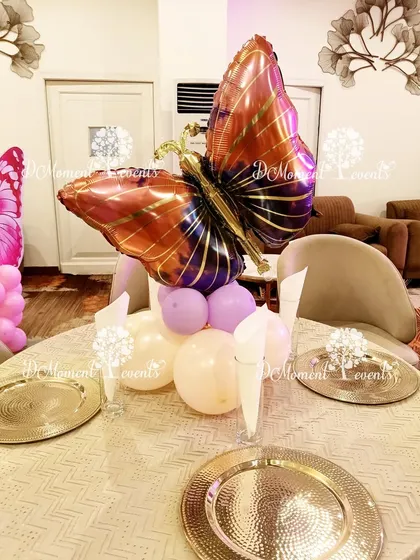 An elegant butterfly foil balloon centerpiece in shades of purple and gold, adding a touch of sophistication to the guest tables.