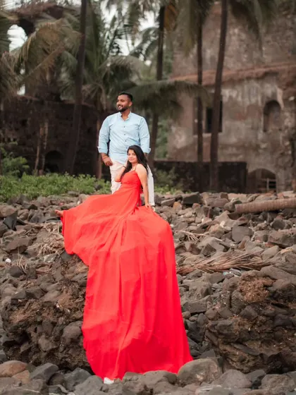 Love against the rocks. The bride looks stunning as her red trail gown cascades down, creating a beautiful contrast of textures and colors for their pre-wedding shoot.