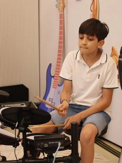 A young drummer lays down the beat for his band at our MuSo showcase. We teach students how to play together, an essential skill for any aspiring musician.