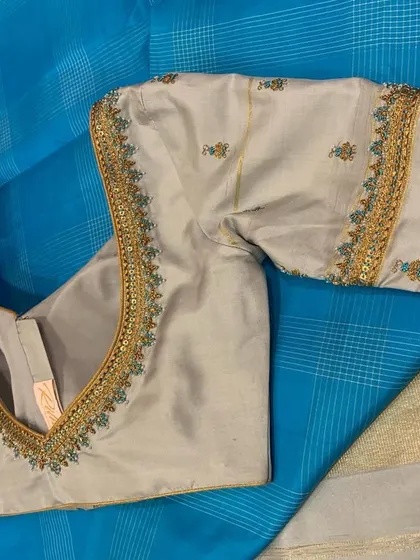 A close-up of the grey blouse, showing the delicate multi-colored floral embroidery.