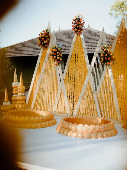 A closer look at the triangle backdrop, with its vibrant floral arrangements and traditional props. This setup is perfect for a couple looking for a unique and stylish Haldi.