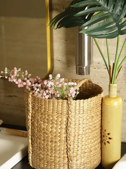 A versatile woven basket used as a decorative holder in a bathroom. Filled with delicate pink flowers, it demonstrates how our storage solutions can also serve as beautiful, rustic vases or planters to enhance your decor.