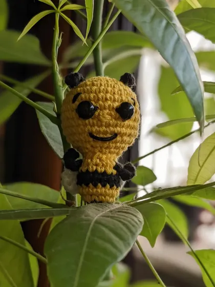 The honey bee bookmark sitting playfully in a houseplant.