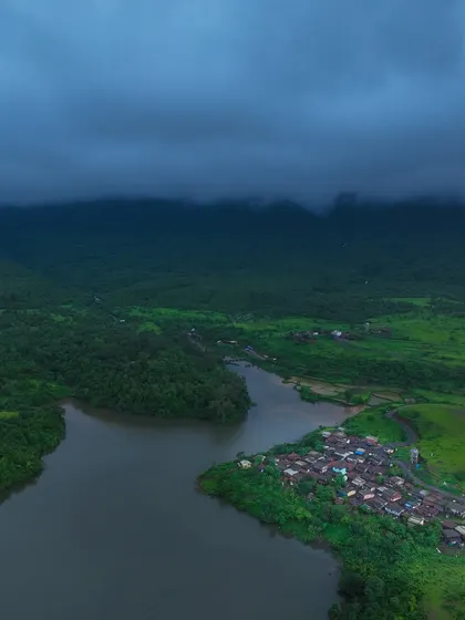 The village of Kondeshwar under dark monsoon clouds. The mood is dramatic and beautiful, showcasing the power of the approaching rain.