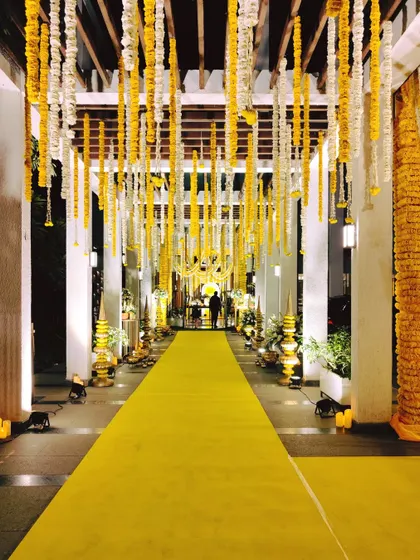A longer view of the entrance walkway for the Sai Sandhya, showing how the overhead floral strings and side lighting create a grand and spiritual passage.