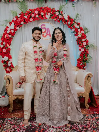A joyful portrait of the newly engaged couple in front of their floral backdrop.