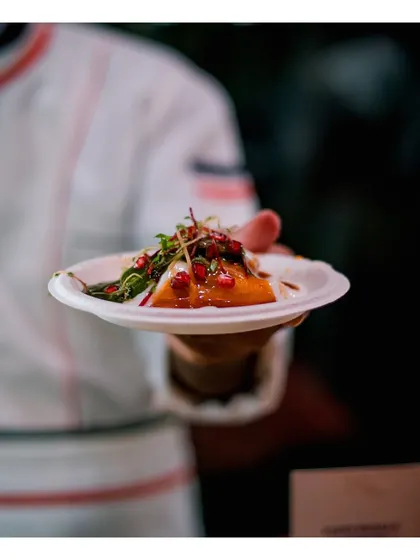 A beautifully plated Indian fusion dish, showcasing fresh elements like pomegranate and microgreens, held by a chef ready for service.