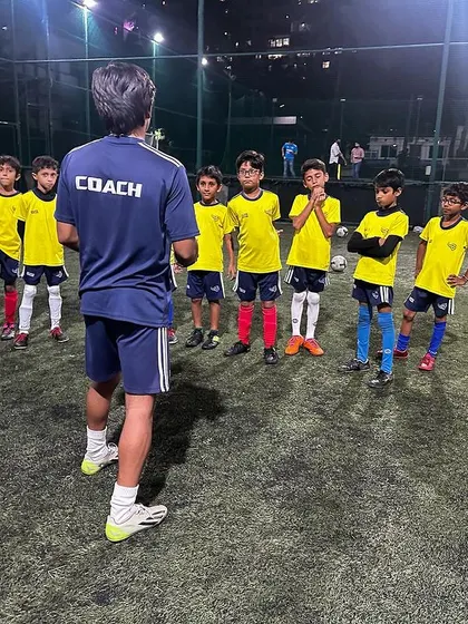 A coach addresses the advanced Under-9 group before a drill. Clear instructions and setting expectations are crucial for a productive session.