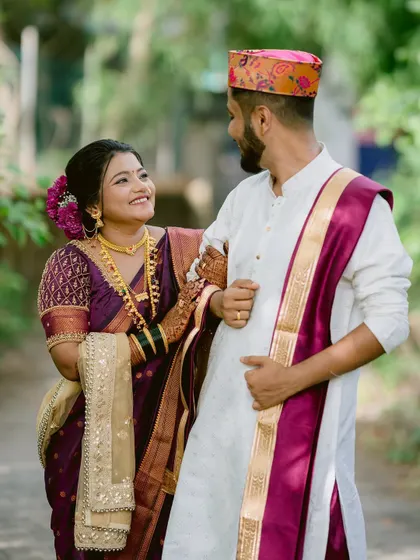 The couple walking together, the groom in his traditional cap and the bride in her vibrant saree.